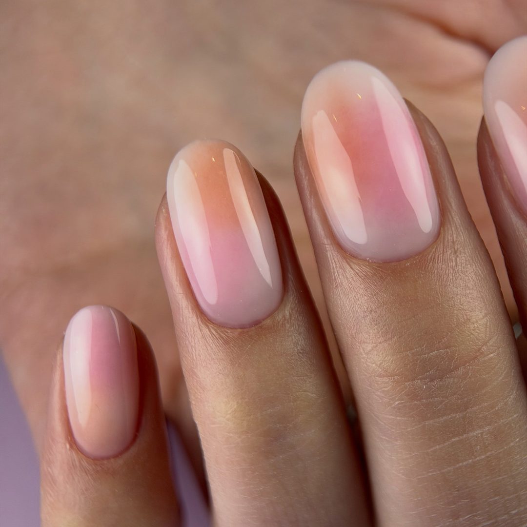 Aura nailart in zacht roze en perzik op ovale nagels
